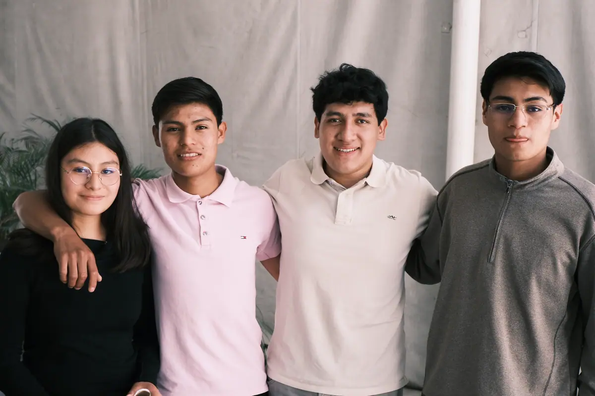 Cuatro jóvenes de la iglesia, abrazados y sonriendo a la cámara.
