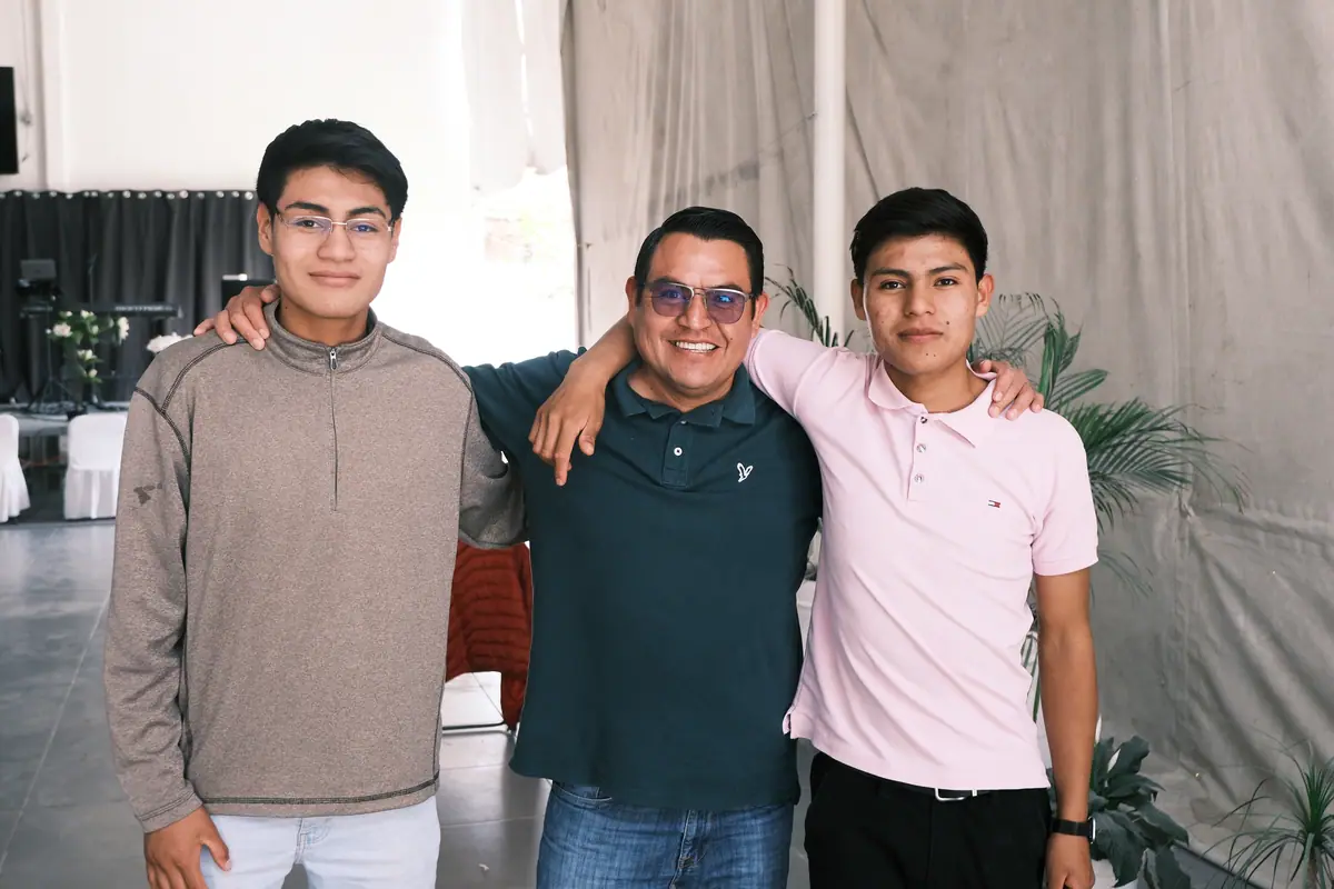 Tres hombres de la iglesia, abrazados, sonríen a la cámara.