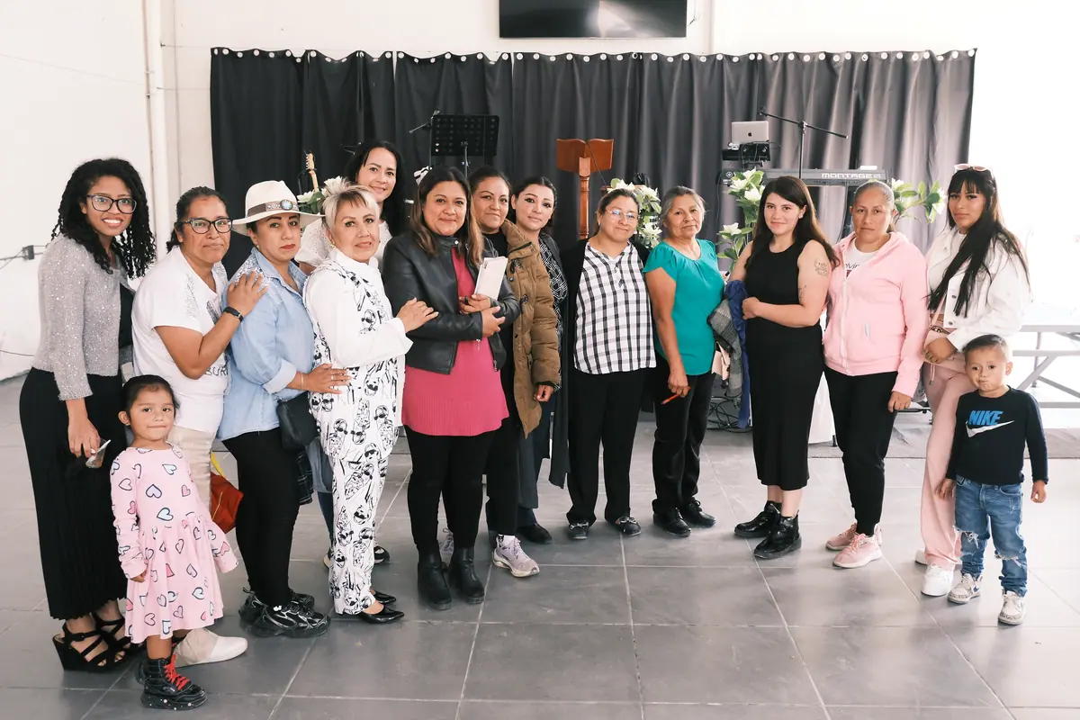Mujeres y niños de la congregación posan juntos en el salón de la iglesia.