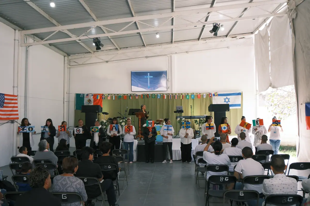 Interior del templo: sillas para la congregación, el escenario al fondo y banderas de distintos países colgadas.